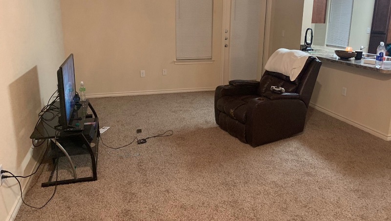 A sparse room with only a chair and a tv